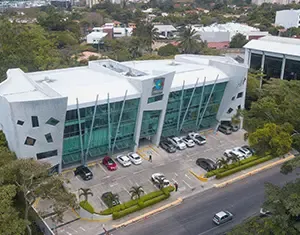 Fachada vanguardista de cristal en edificio corporativo de oficinas, diseñado con excelencia por nuestra desarrolladora inmobiliaria. Edificio de oficinas moderno con fachada de vidrio y estacionamiento, un proyecto de nuestra desarrolladora inmobiliaria.